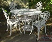 Victorian Style Cast Aluminum Patio Table, Umbrella Stand & 4 Chairs. Table is 41" diameter & the chairs have fancy floral decoration.