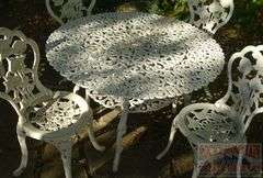Victorian Style Cast Aluminum Patio Table, Umbrella Stand & 4 Chairs. Table is 41" diameter & the chairs have fancy floral decoration.