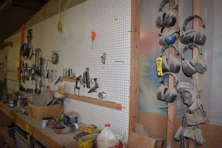 CONTENTS ON WORKBENCH AND PEG BORAD INCLUDING EAR PROTECTION, WRENCHES, SAWS AND CLAMPS