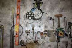 CONTENTS ON WORKBENCH AND PEG BORAD INCLUDING EAR PROTECTION, WRENCHES, SAWS AND CLAMPS