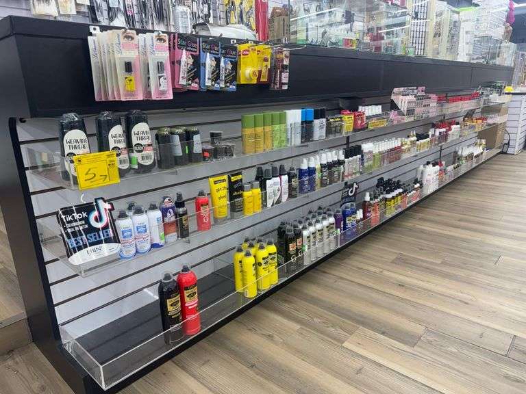 Row of Beauty Supply Products w/ Plexiglass Shelves. Includes Weaving Threads, Eyelash Glue, Lip Balms, Hair Styling Glues, Mouses, and Sprays, Hair Conditioners, Eyeliners, and Lipsticks