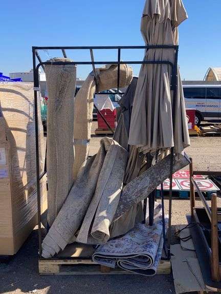 Metal frame palette with assorted patio umbrellas and throw rugs ...