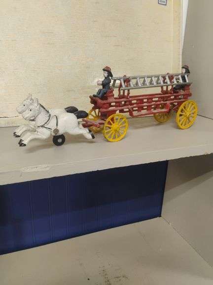 Cast iron toy fire wagon ,drawn by white horses, carrying two ladders, and two firemen . Marked Tai