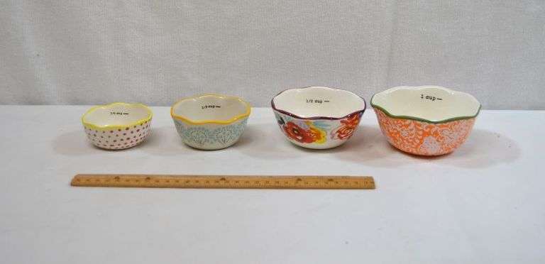 SET OF 4 PIONEER WOMAN NESTING MEASURING BOWLS. THE 1/4 CUP BOWL HAS A SMALL CRACK