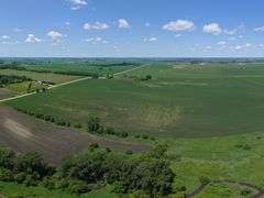 Drone view of 118.86 acres of farmland for sale in Floyd County, Iowa, showcasing expansive row crop fields and rural Iowa landscape under a clear sky.