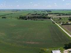 Drone view of 118.86 acres of farmland for sale in Floyd County, Iowa, showcasing expansive row crop fields and rural Iowa landscape under a clear sky.