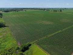 Drone view of 118.86 acres of farmland for sale in Floyd County, Iowa, showcasing expansive row crop fields and rural Iowa landscape under a clear sky.
