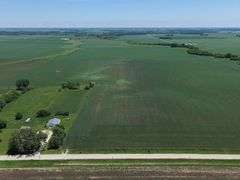 Drone view of 118.86 acres of farmland for sale in Floyd County, Iowa, showcasing expansive row crop fields and rural Iowa landscape under a clear sky.