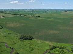 Drone view of 118.86 acres of farmland for sale in Floyd County, Iowa, showcasing expansive row crop fields and rural Iowa landscape under a clear sky.