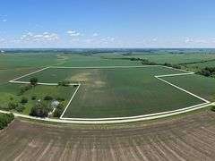 Aerial view of 118.86 acres of farmland for sale in Floyd County, Iowa, outlined in white against a backdrop of lush green fields and open countryside.