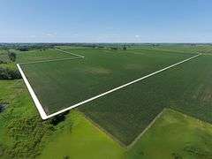 Aerial view of 118.86 acres of row crop farmland for sale in Floyd County, Iowa, outlined in white with lush green fields and clear skies.