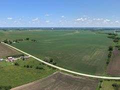 Drone view of 118.86 acres of farmland for sale in Floyd County, Iowa, showcasing expansive row crop fields and rural Iowa landscape under a clear sky