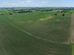 Drone view of 118.86 acres of farmland for sale in Floyd County, Iowa, showcasing expansive row crop fields and rural Iowa landscape under a clear sky.
