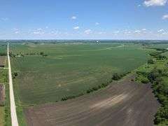 Drone view of 118.86 acres of farmland for sale in Floyd County, Iowa, showcasing expansive row crop fields and rural Iowa landscape under a clear sky.