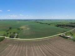 Drone view of 118.86 acres of farmland for sale in Floyd County, Iowa, showcasing expansive row crop fields and rural Iowa landscape under a clear sky.
