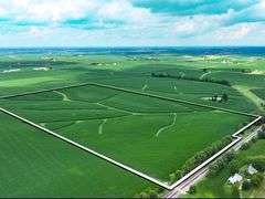 Elevated drone photo of a 70-acre Washington County, Iowa row-crop field—outlined in white—showing gently rolling soybean ground with contour waterways and tree-lined borders.