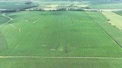 Aerial view of a 72-acre Washington County, Iowa row-crop field for sale—uniform green soybeans on gently rolling ground bordered by grass waterways and a nearby paved highway.