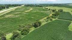 Aerial view of a 30-acre Washington County parcel for sale, featuring a central grassland plateau bordered by lush row-crop fields, scattered trees, and rolling farmland.