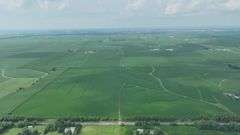Aerial view of a 72-acre Washington County, Iowa row-crop field for sale—uniform green soybeans on gently rolling ground bordered by grass waterways and a nearby paved highway.