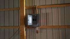 Interior of a spacious machine shed on a 42-acre Washington County, Iowa farm for sale—showing steel siding, open truss roof, concrete floor, and parked farm trailers.