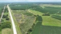 Aerial view of a 30-acre Washington County tract for sale, showing a mix of open crop ground and grassland bordered by a paved highway and surrounded by larger cornfields.
