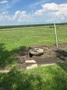 Ground-level view of a steel utility tower frame and capped concrete well beside a metal machine shed on a 42-acre Washington County, Iowa farm for sale.