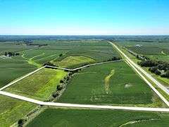 Elevated drone photo of a 30-acre Washington County, Iowa parcel—outlined in white—showing a mix of row-crop fields, grassland, shelterbelt trees, and paved-road frontage.