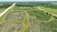 Aerial view of a 30-acre Washington County tract for sale, showing a mix of open crop ground and grassland bordered by a paved highway and surrounded by larger cornfields.