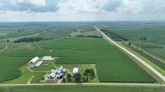 Aerial drone view of a 77-acre Washington County, Iowa row-crop farm for sale—continuous green soybean fields bordered by two paved roads and set amid rolling countryside.