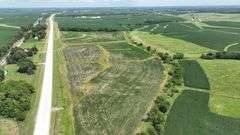 Aerial view of a 30-acre Washington County tract for sale, showing a mix of open crop ground and grassland bordered by a paved highway and surrounded by larger cornfields.