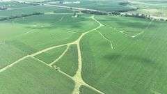 Aerial drone view of 70 contiguous acres of Washington County cropland for sale—lush soybean fields patterned with branching grass waterways and bordered by a tree-lined rail spur.