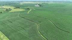 High-elevation drone view of rolling Washington County cornfields with sweeping contour rows and a distant farmstead—part of a 106-acre tract for sale.