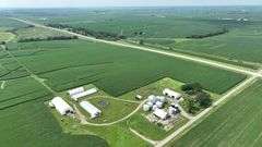 Aerial drone view of a 77-acre Washington County, Iowa row-crop farm for sale—continuous green soybean fields bordered by two paved roads and set amid rolling countryside.