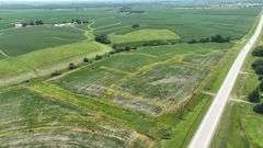 Aerial view of a 30-acre Washington County tract for sale, showing a mix of open crop ground and grassland bordered by a paved highway and surrounded by larger cornfields.