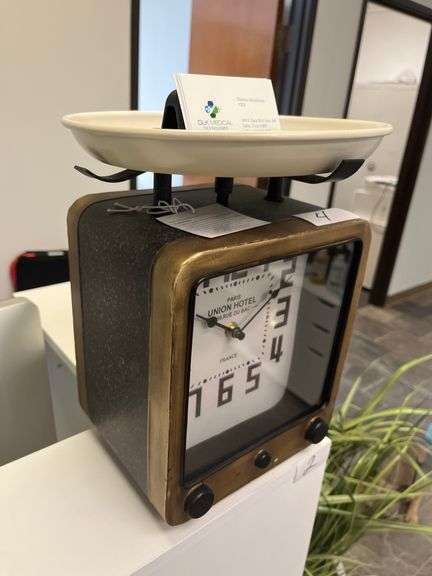 vintage scale clock with a wooden frame, large black numerals, and a white weighing platform on top.