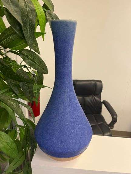 Tall, slender blue ceramic vase with a smooth, matte finish,