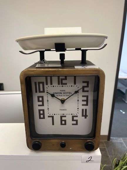 vintage scale clock with a wooden frame, large black numerals, and a white weighing platform on top.