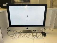 Apple iMac 21.5-inch desktop computer with a white keyboard and Logitech mouse on a desk. The 21.5-inch iMac was part of Apple's Intel-based lineup, offering a 4K Retina display