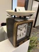 vintage scale clock with a wooden frame, large black numerals, and a white weighing platform on top.